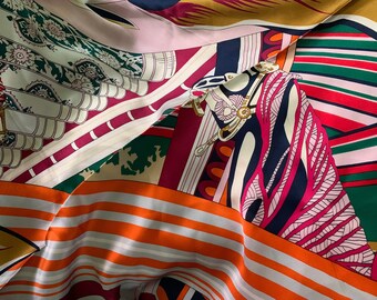 May include: A patterned silk scarf in a variety of colours. The design incorporates stripes, floral elements, and a horse illustration. The colour scheme includes orange, red, pink, green, and navy blue. The scarf is made of silk.
