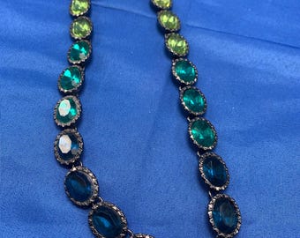 An ombré necklace of oval green into blue crystals.