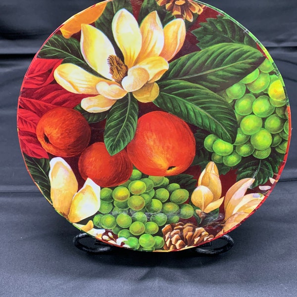 A round decorative cardboard storage box covered in primarily Christmas flowers and fruit.