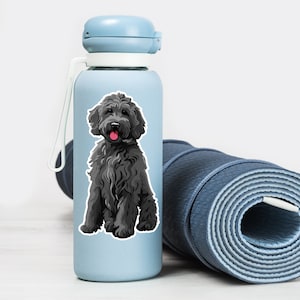 Puede incluir: Una botella de agua azul con una pegatina de perro doodle en blanco y negro en el lateral. La botella est&aacute; al lado de una esterilla de yoga azul enrollada.
