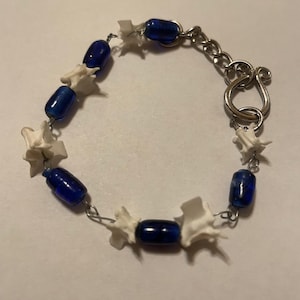 Puede incluir: Una taza de cerámica blanca con un asa negra y el texto "But First, Coffee" en negrita negra. La taza probablemente tiene 325 ml de capacidad y está sobre una superficie blanca.