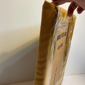 May include: A wrapped canvas art piece with a mustard-coloured fabric edge. The cardboard packaging is sealed with clear tape and features the text "HANDLE WITH CARE" and "GLASS". The art piece is from "Homeco, Inc."