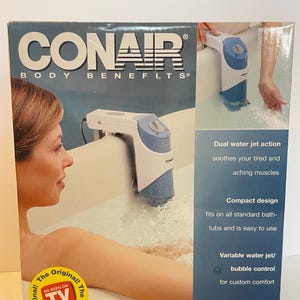 May include: Conair Bath Spa box with a woman in a bathtub. The box features a white and blue water jet spa device. Text on the box reads "Dual water jet action" and "Powerful Water Jet BATH SPA."