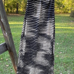 May include: A black and white patterned maxi dress with thin straps. The dress has a gathered detail at the bust and a straight skirt.