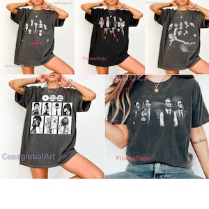 May include: A collection of five charcoal gray and black oversized t-shirts featuring various graphic prints of musical groups and individuals in monochromatic tones. Each shirt has short sleeves, a crew neckline, and a relaxed, loose-fitting silhouette.