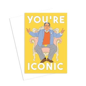 Peut inclure: Une carte jaune avec le texte "YOU'RE ICONIC" en blanc. Une illustration de dessin animé d'une personne assise sur un trône avec un coussin rose.