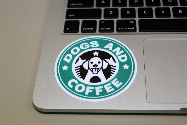 Puede incluir: Una pegatina verde y blanca con el texto "DOGS AND COFFEE" y una silueta en blanco y negro de la cabeza de un perro en el centro.