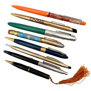 May include: A collection of eight vintage pens, including a bright orange pen with the text "CNRAIL" and a blue pen with the text "CHICAGO ILLINOIS".
