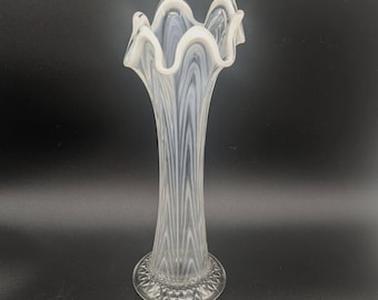 May include: A white milk glass vase with a ruffled top and a clear, textured base. The vase has a striped pattern.