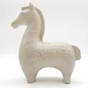 May include: White ceramic horse figurine with intricate geometric patterns carved into the surface.