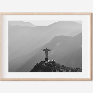 Puede incluir: Una fotografía en blanco y negro de la estatua del Cristo Redentor en Río de Janeiro, Brasil. La estatua se alza sobre una montaña con un fondo brumoso.