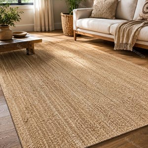 Op de afbeelding: Een rechthoekig vloerkleed in een natuurlijke bruine kleur met een geweven, getextureerd oppervlak. Het kleed is gemaakt van gevlochten vezels, wat zorgt voor een consistent, dicht patroon over het gehele oppervlak als neutrale basis.