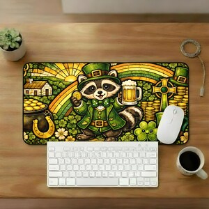 May include: A St. Patrick's Day themed desk mat featuring a cartoon raccoon dressed in green, holding a coin and a beer mug. The design includes a rainbow, gold coins, a horseshoe, and shamrocks. A white keyboard and mouse are also visible.