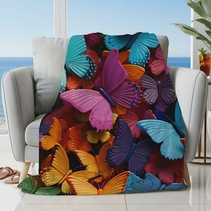May include: A soft fleece throw blanket featuring a vibrant, dense pattern of butterflies in various colors including bright pink, deep purple, orange, yellow, and shades of blue, layered closely together to create a colorful, nature-inspired design.