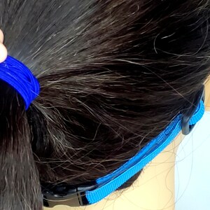 May include: A blue strap with black buckles. The strap is designed to hold glasses or goggles in place.