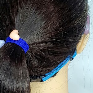 May include: A blue adjustable strap with a black buckle. The strap is designed to hold a face mask in place behind the ears.