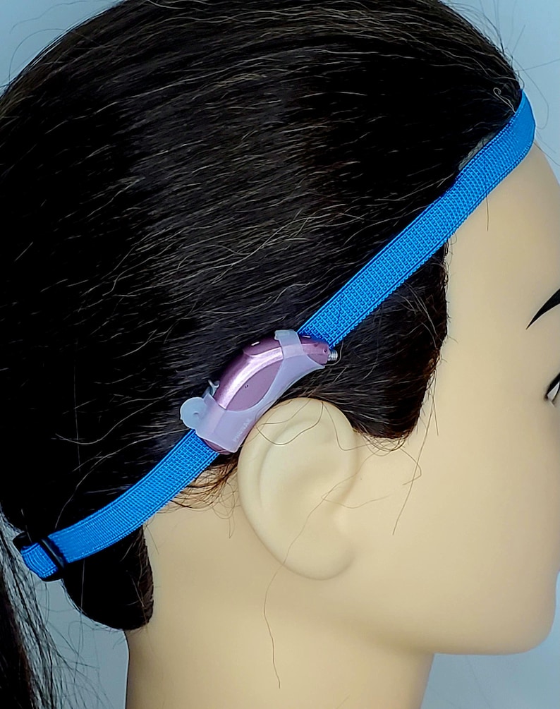 May include: A blue headband with a hearing aid attached to it. The headband is made of a soft, stretchy material and has a secure fit. The hearing aid is small and discreet, and it is designed to be comfortable to wear for extended periods of time.