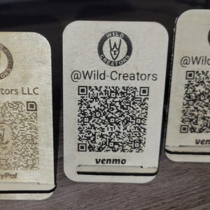 May include: Three wooden business card holders with a logo and QR code. The logo is a stylized wolf head with the text "Wild Creators". The QR codes are for PayPal, Venmo, and @Wild-Creators.