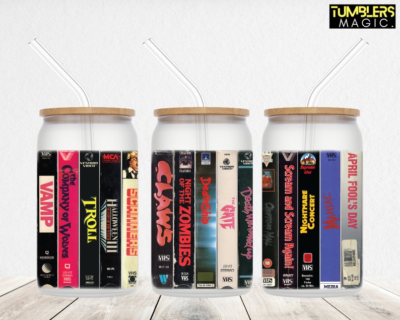 May include: Three clear glass tumblers with bamboo lids and straws. Each tumbler features a different set of vintage VHS tapes with horror movie titles, including "Vamp", "Troll", "Halloween III", "Claws", "Night of the Zombies", "Death Ship", "The Gate", "Death Warmed Up", "Chopping Mall", "Scream and Scream Again", "Nightmare Concert", "Maniac", and "April Fool's Day".