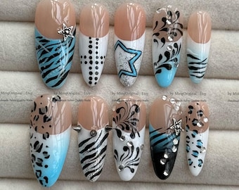 May include: A collection of ten artificial nails with various designs. The nails feature a nude base with designs including zebra stripes, stars, dots, and floral patterns. Some nails have rhinestones and a star-shaped charm. The nails are in an oval shape.