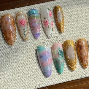 May include: Ten different nail designs featuring a variety of colors and patterns, including floral, abstract, and glitter. The nails are all long and almond-shaped.
