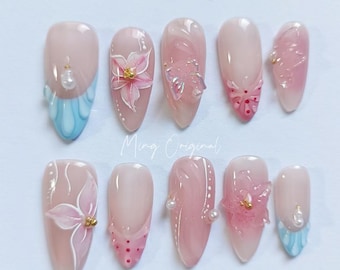 Può includere: Dieci punte per unghie rosa e bianche con diversi design, tra cui fiori, farfalle e pois. Le punte sono decorate con accenti dorati e perlati. Ming Original.