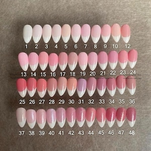 Puede incluir: Una colección de cuarenta y ocho uñas postizas en forma de almendra dispuestas en cuatro filas de doce. Cada uña presenta un estilo de manicura francesa con punta blanca y un color base que va desde el nude transparente hasta tonos rosa y brillo.
