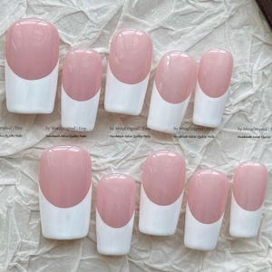 May include: A set of ten press-on nails featuring a classic French manicure design with a soft pink base and opaque white tips. Each nail has a smooth, glossy finish and a rounded square shape. The text MingOriginal Etsy is visible.