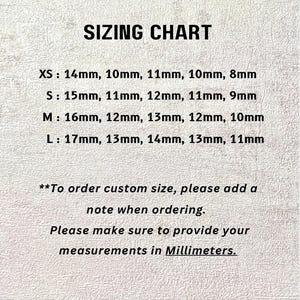 May include: A sizing chart with black text on a textured off-white background. It lists sizes XS, S, M, and L with corresponding measurements in millimeters. It includes instructions to add a note for custom sizes and provide measurements in millimeters.