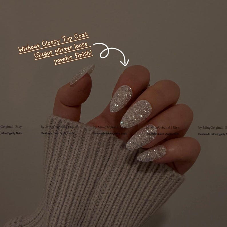K&ouml;nnte beinhalten: Nahaufnahme einer Hand mit langen, stilettof&ouml;rmigen N&auml;geln, die mit silbernem Glitzer bedeckt sind. Der Text lautet "Without Glossy Top Coat (Sugar glitter loose powder finish)". Die N&auml;gel haben ein funkelndes, strukturiertes Finish.
