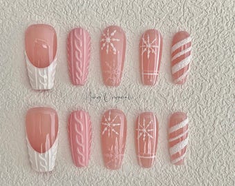 May include: Set of ten pink and white false nails with different winter-themed designs, including snowflakes, candy canes, and cable knit patterns.