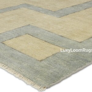 Pode incluir: Um tapete de &aacute;rea azul claro e bege com um padr&atilde;o geom&eacute;trico. O tapete tem uma borda de franjas e o texto "LuxyLoomRugs" &eacute; vis&iacute;vel no canto inferior direito.