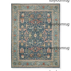 May include: A rectangular, patterned rug with a dark blue central field and a detailed border. The rug features a complex design with floral and geometric elements in shades of teal, coral, and beige. The text "luxyloomrug" is visible in the image.