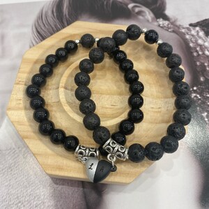 May include: Two black beaded bracelets with silver accents and a heart charm with the letters "L" and "A" engraved on it.