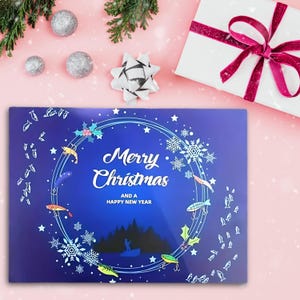 May include: A blue Christmas card with the words "Merry Christmas and a Happy New Year" in white script. The card features a circular design with fishing lures, snowflakes, and a silhouette of a person fishing. A white gift box with a pink ribbon is in the background.