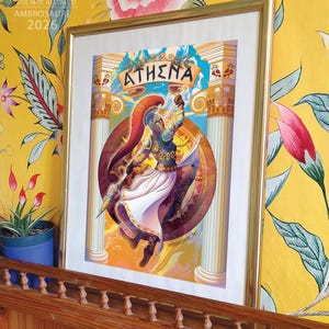 May include: A framed art print featuring a central illustration of the Greek goddess Athena in armor, holding a spear and shield. The artwork includes two classical columns, a banner with the text ATHENA, and a circular background design.