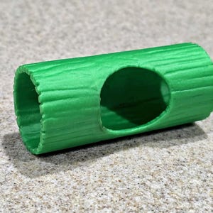 May include: A vibrant green pet tunnel, resembling a log with a textured surface. It has a circular opening on the side. The cylindrical structure is designed for small animals, offering a playful habitat.