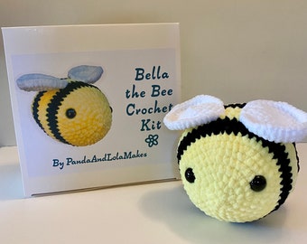 Peut inclure: Un kit de crochet pour réaliser une abeille jaune et noire nommée Bella. Le kit comprend de la laine, du rembourrage et des instructions. La boîte porte le texte "Bella the Bee Crochet Kit" et "By PandaAndLolaMakes".