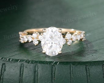 May include: A gold engagement ring with a large oval-shaped center stone and smaller round stones set in a delicate band. The ring is on a green background.