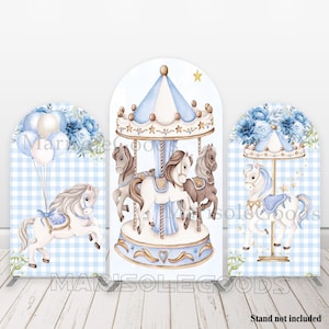 May include: A three-panel backdrop featuring a carousel theme. The central panel showcases a carousel with horses in shades of brown and white, under a blue and white striped canopy. The side panels have a horse, balloons, and floral arrangements.