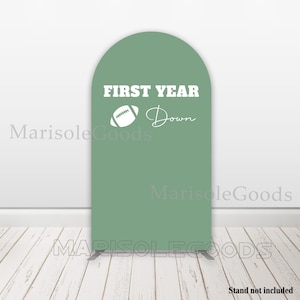May include: A green arch-shaped backdrop with the text "FIRST YEAR Down" and a white football graphic.