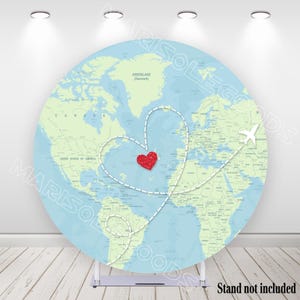 May include: A round backdrop featuring a world map in shades of blue and green. A dotted line forms a heart shape over the Atlantic Ocean, with a red glitter heart in the center. A white airplane graphic is also present. The text "Stand not included" is at the bottom.