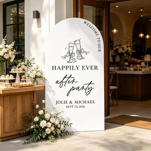 May include: A white arched sign featuring black text that reads WELCOME TO OUR HAPPILY EVER after party JOLIE & MICHAEL SEPT 23, 2026. The sign includes a black line drawing of two champagne flutes with bows and ribbons at the top center.