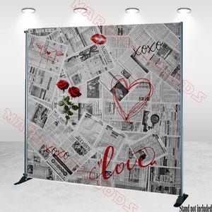 May include: A backdrop featuring a collage of newspaper clippings with red accents. The design includes red roses, a heart, the word "love", and "xoxo". The backdrop is supported by a black metal frame.