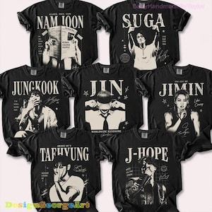 May include: A collection of seven black t-shirts featuring graphic prints of individual performers. Each shirt displays a name in large white lettering, a portrait of the person, and decorative elements like stars, grids, and handwritten-style signatures.