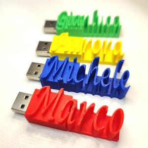 May include: Four USB flash drives with names in a cursive font. The names are Gianna (green), Aurora (yellow), Michele (blue), and Marco (red). The USB connectors are silver.