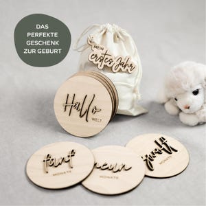 Puede incluir: Un conjunto de discos de madera para hitos de bebé con letras cortadas con láser. Los discos incluyen frases y marcadores de mes. También se incluye una bolsa con cordón y una etiqueta de madera con "Mein erstes Jahr".