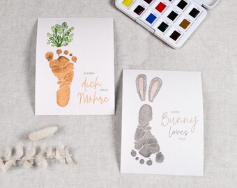 Könnte beinhalten: Zwei weiße Karten mit Fußabdruck-Kunst. Eine Karte hat einen Fußabdruck mit einem Pflanzendesign und dem Text "Ich mag dich volle Möhre". Die andere Karte hat einen Fußabdruck mit Hasenohren und dem Text "Some Bunny loves you!"