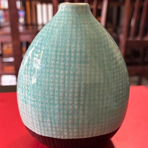 Unique blue glazed bud vase, textured light blue checkered pattern, black base.