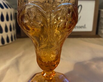 Vintage marigold color Carnival Glass pedestal goblet, embossed floral design.